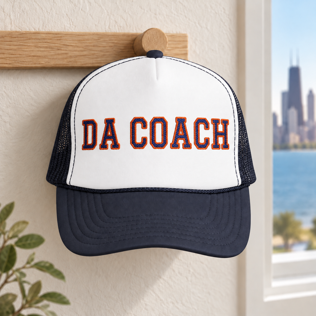 Da Coach embroidered foam trucker hat in white and navy on a wall hook