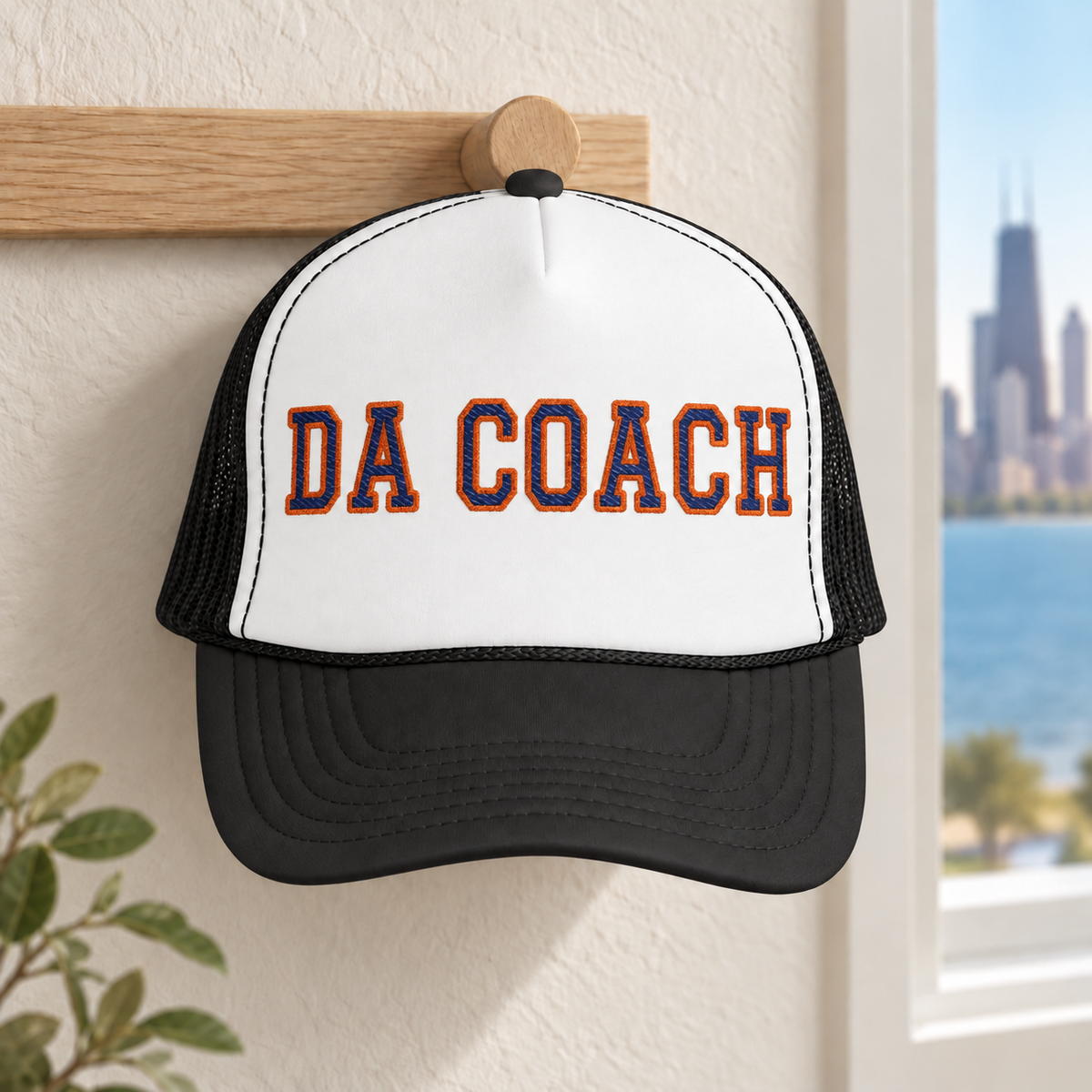 Da Coach embroidered foam trucker hat in white and black on a wall hook