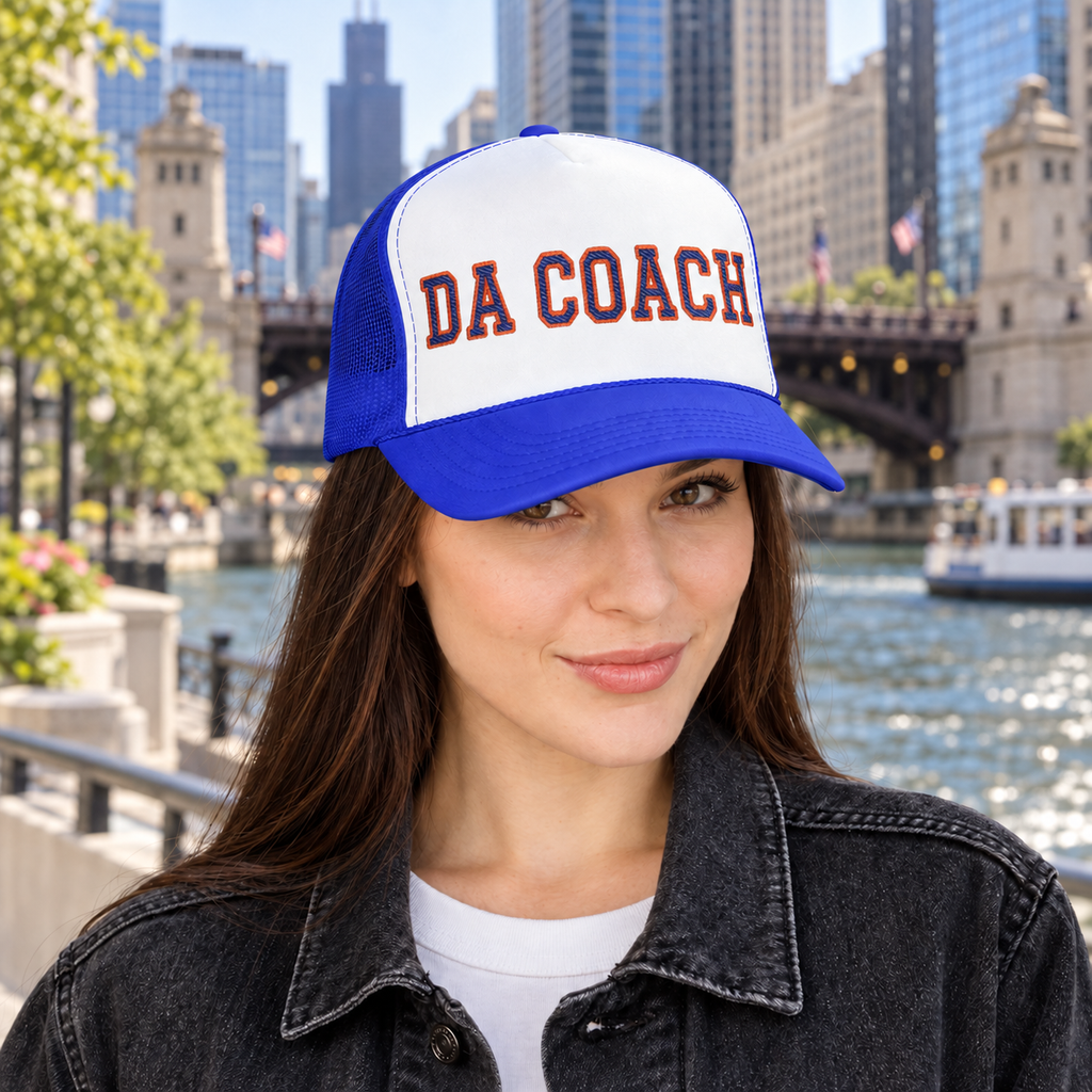 Woman wearing the Da Coach embroidered foam trucker hat in white and royal blue on the Chicago Riverwalk