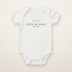 Little Chicagoan baby bodysuit in White, flat lay with gold script and four red stars