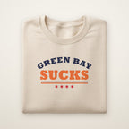 Green Bay Sucks Varsity crewneck in Sand, flat lay with navy and orange varsity lettering