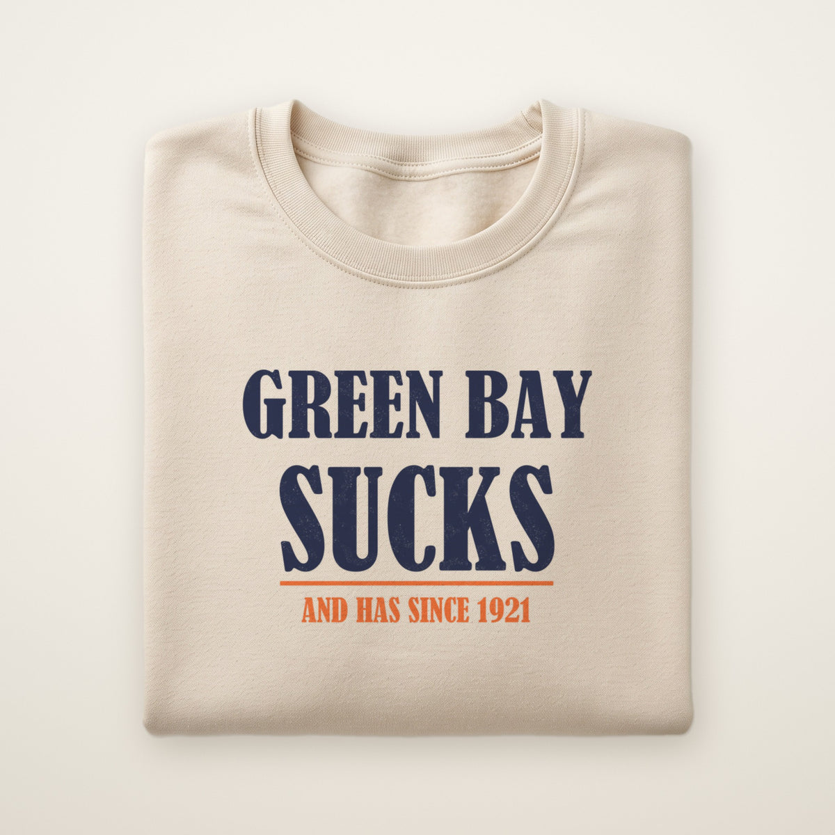 Green Bay Sucks And Has Since 1921 crewneck in Sand, flat lay with navy block type