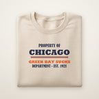 Property of Chicago Green Bay Sucks Dept. crewneck in Sand, flat lay with navy and orange print