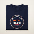 Green Bay Sucks Social Club crewneck in Navy, flat lay with circular Chicago Chapter badge