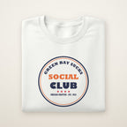 Green Bay Sucks Social Club crewneck in White, flat lay with navy and orange circle badge