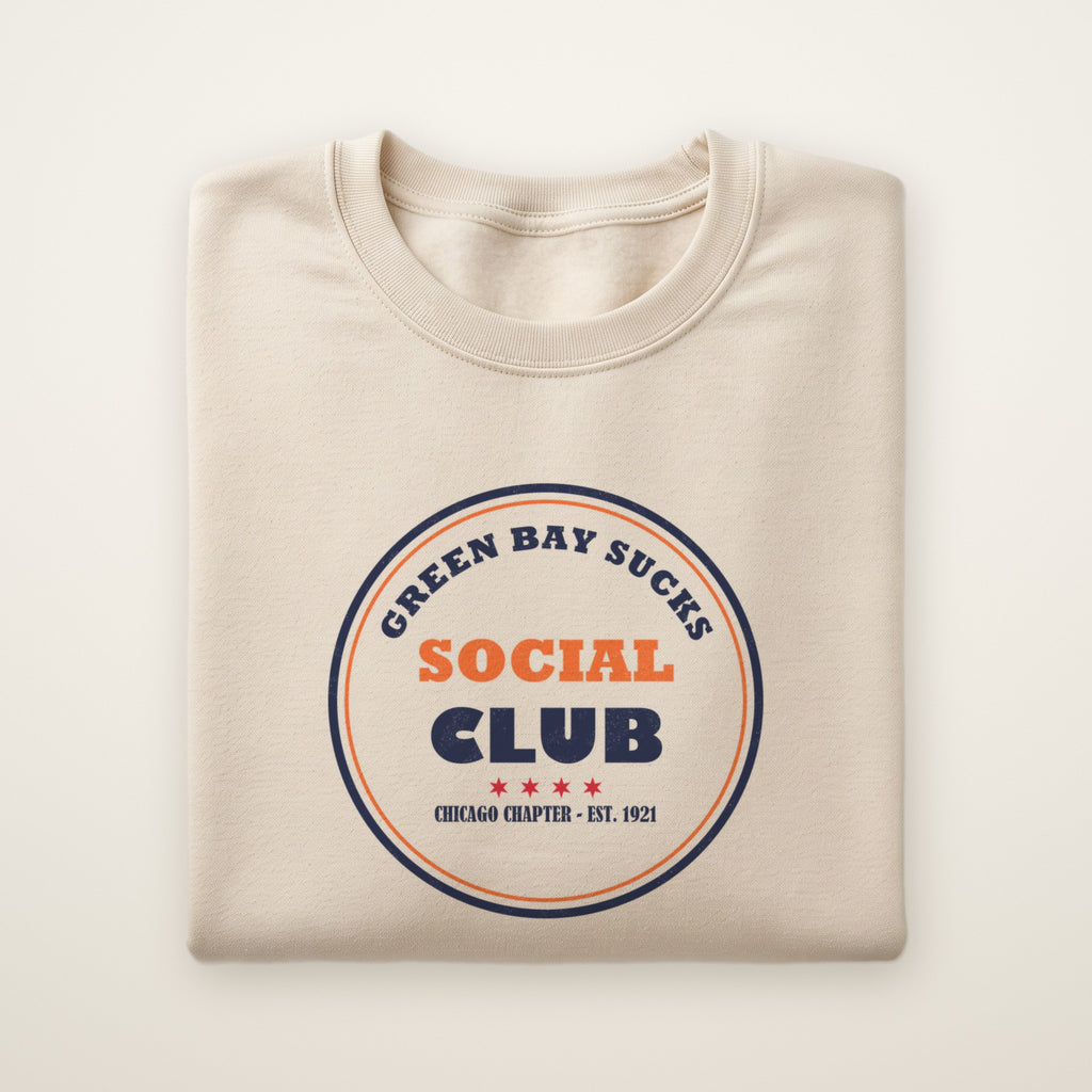 Green Bay Sucks Social Club crewneck in Sand, flat lay with navy and orange circle badge