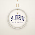 Bridgeport Chicago Christmas Ornament, Est. 1836 hanging on a gold cord, ivory backdrop