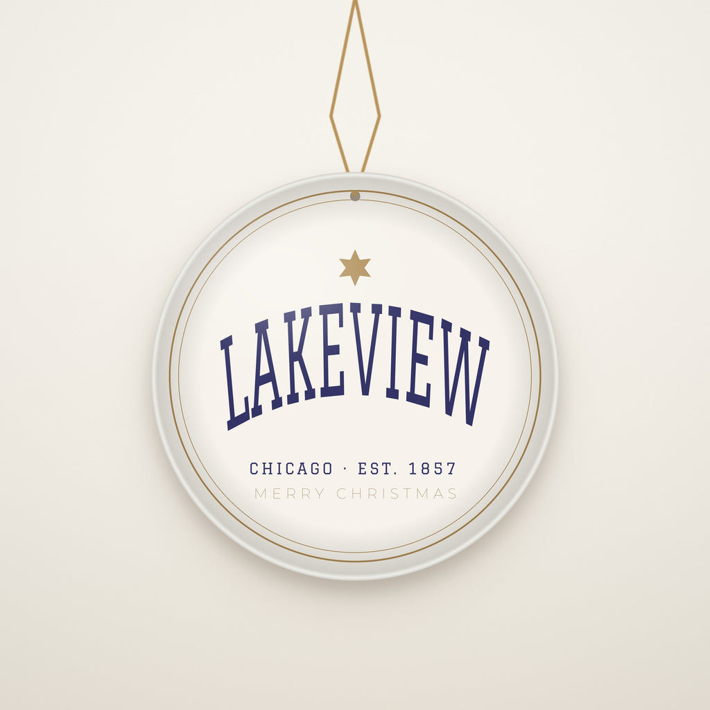 Lakeview Chicago Christmas Ornament, Est. 1857 hanging on a gold cord, ivory backdrop