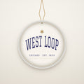 West Loop Chicago Christmas Ornament, Est. 1853 hanging on a gold cord, ivory backdrop