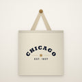 Chicago Est. 1837 Canvas Tote Bag hanging from a brass peg on an ivory wall