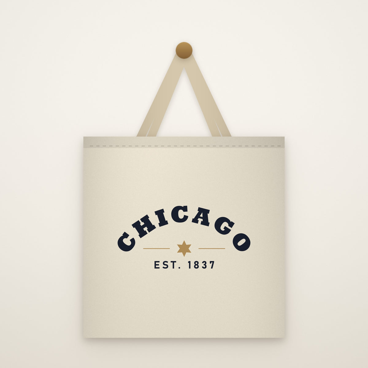 Chicago Est. 1837 Canvas Tote Bag hanging from a brass peg on an ivory wall