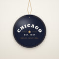 Chicago Est. 1837 Ceramic Christmas Ornament hanging on a gold cord, ivory backdrop
