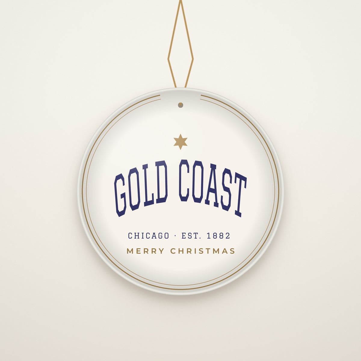 Gold Coast Chicago Christmas Ornament, Est. 1882 hanging on a gold cord, ivory backdrop