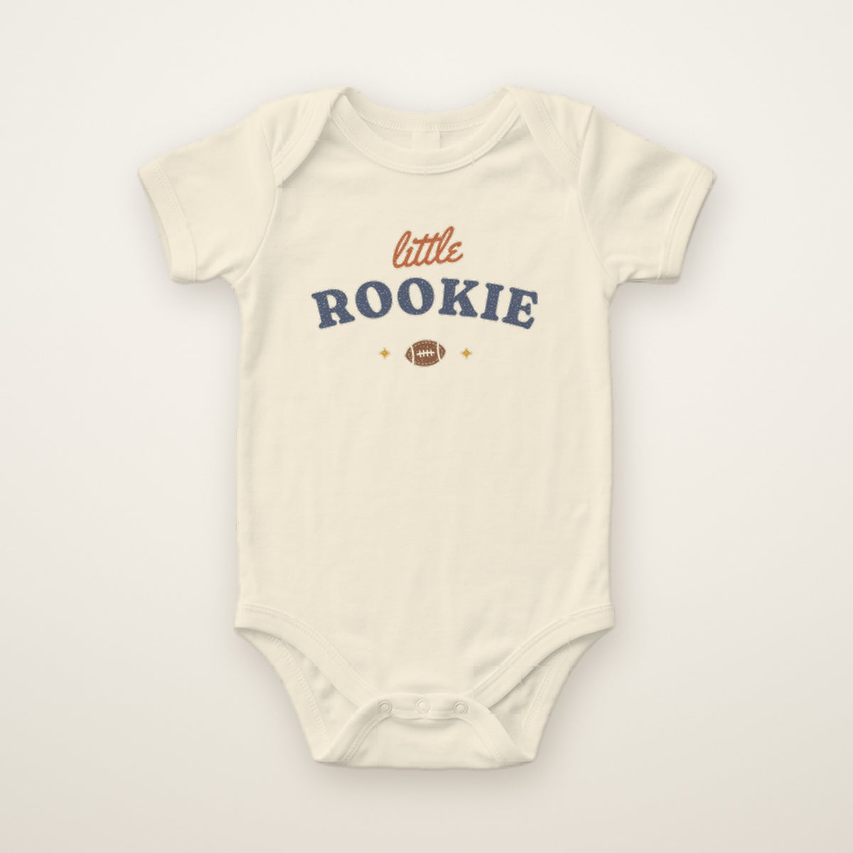 Little Rookie Bodysuit in Natural, flat lay on ivory