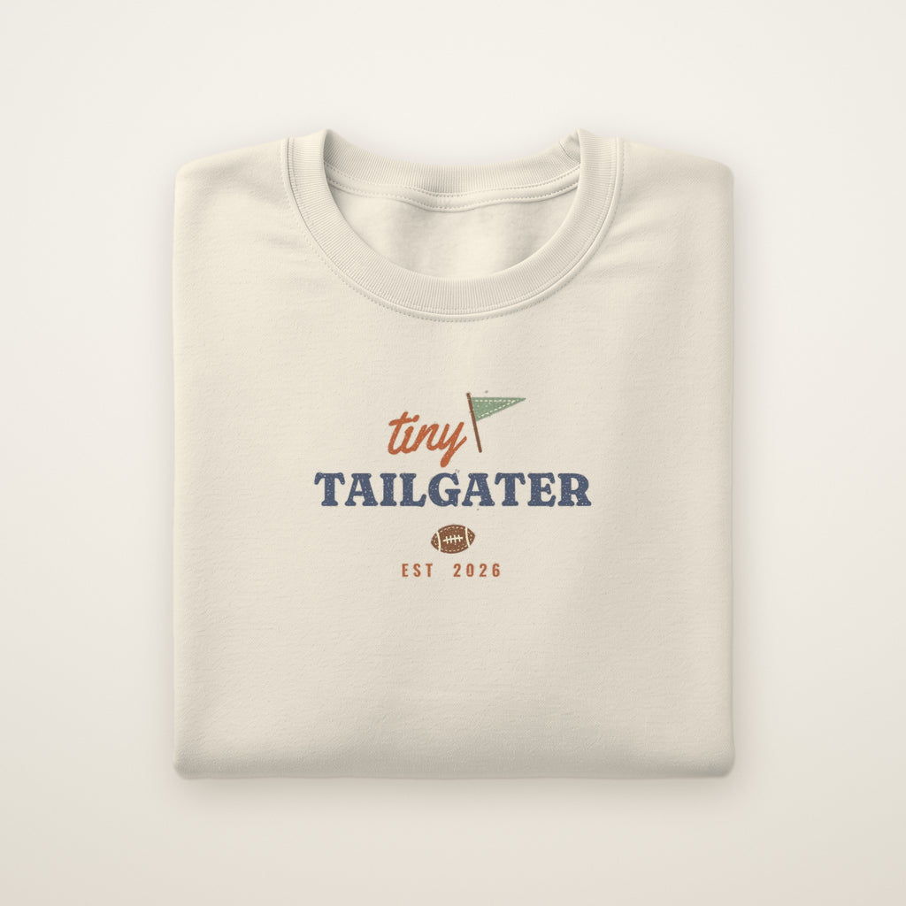 Tiny Tailgater Toddler Crewneck — Est. 2026 in Natural Heather, flat lay on ivory