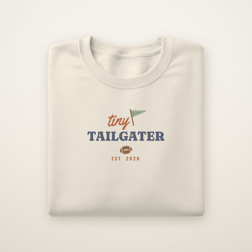 Tiny Tailgater Toddler Crewneck — Est. 2026 in Natural Heather, flat lay on ivory